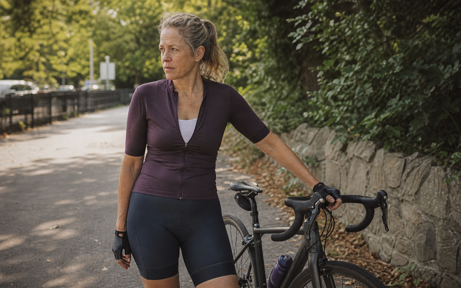 Woman in fitted cycling clothing standing beside her bicycle after a ride